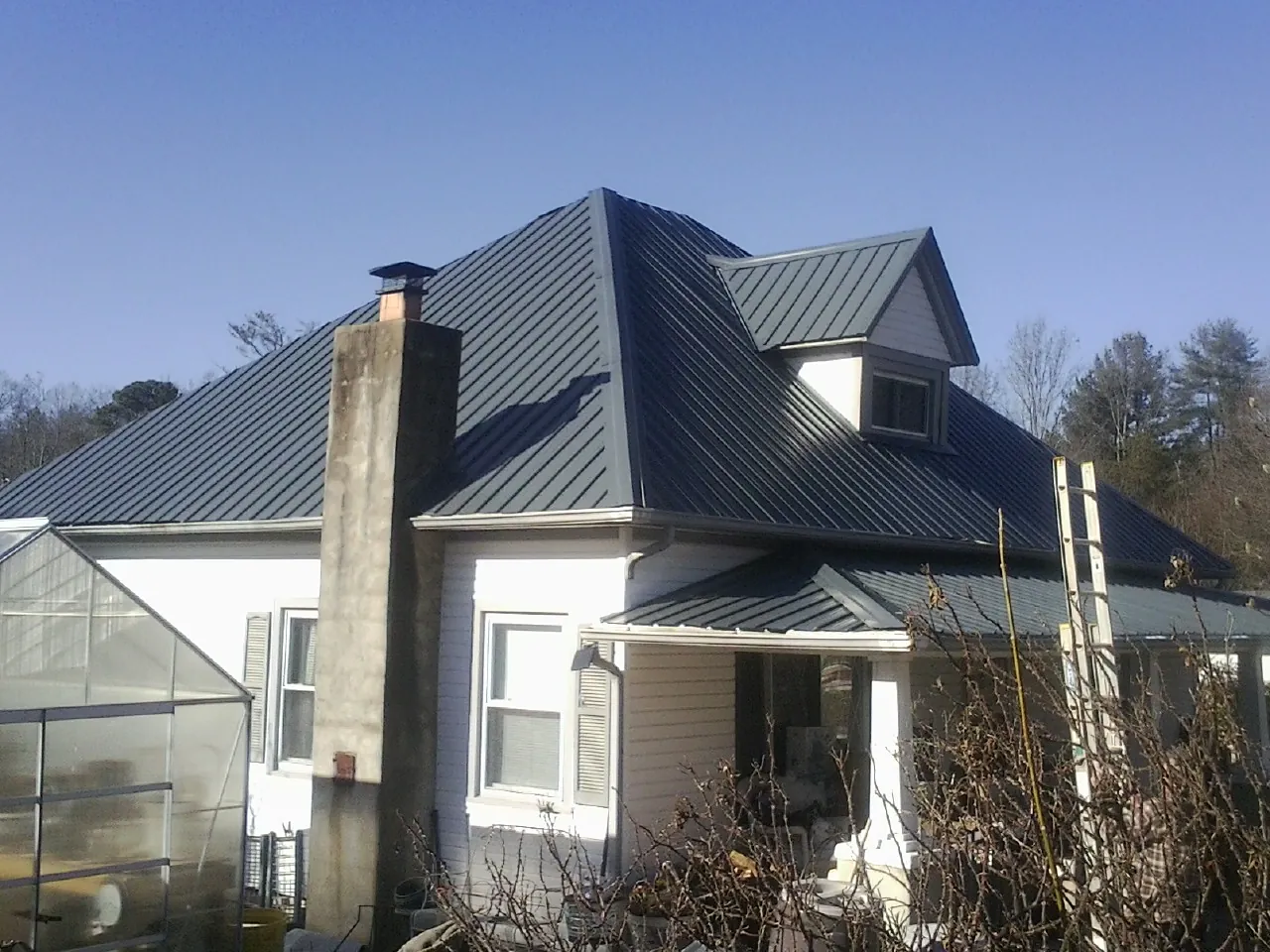 Dark blue standing seam metal roof on a white farmhouse with dormer — Slate & Tile Roof Repair by Roofing Brothers in Frazeysburg