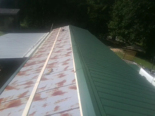 Old rusted panels beside newly installed green metal roofing — Wind Damage Roof Repair by Roofing Brothers in Frazeysburg