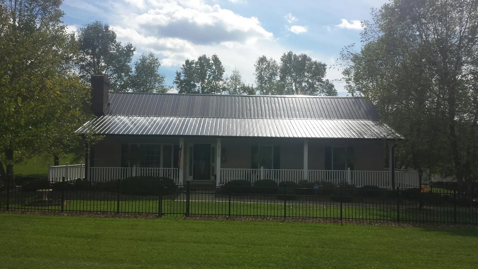 Gray metal roof on a brick ranch with a full width front porch — Gutter Guard Installation work by our crew in Frazeysburg