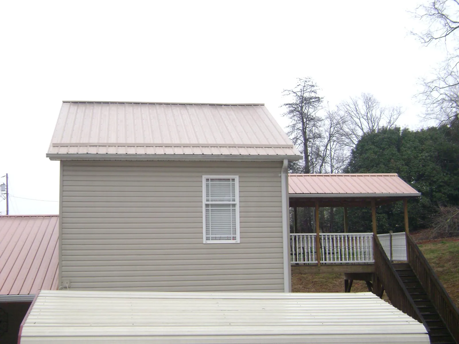 Tan metal roofs on a two story addition and attached porch, from a Roof Replacement job in Frazeysburg