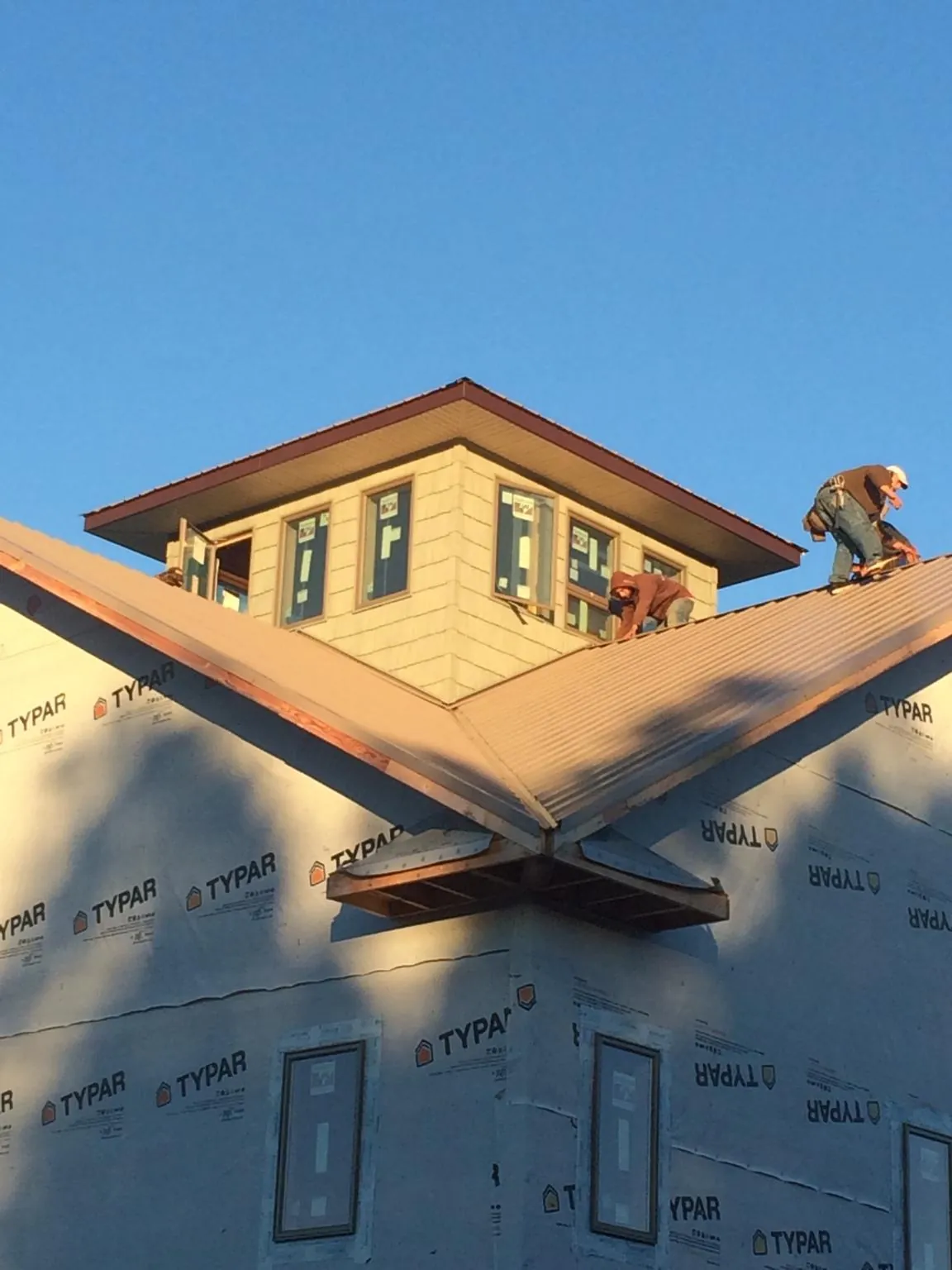 Roofers working around a rooftop cupola on a new metal roof at sunset — Roof Waterproofing in Frazeysburg by Roofing Brothers
